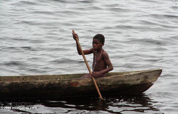 Junge, der ein Dugout-Kanu in einer Lagune nahe Loango Nationalpark in Gabun Loango