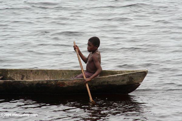 Junge, der ein Dugout-Kanu in einer Lagune nahe Loango Nationalpark Loango