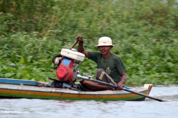 Человек вождения традиционных бугийский моторных каноэ