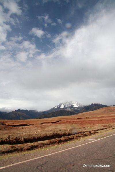 Campo de Cuzco com vista de picos neve-tampados em Peru