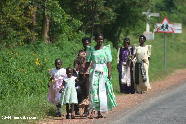Frauen und Kinder oben gekleidet und nach Hause gehend von der Kirche an einem Sonntag in Uganda