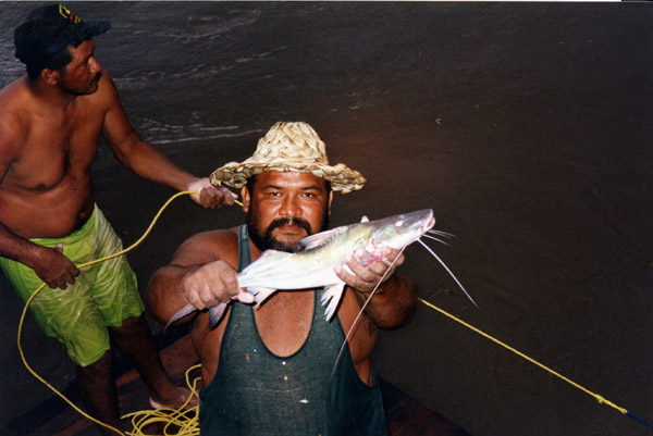 Pescador com um peixe-gato do Rio Carrao
